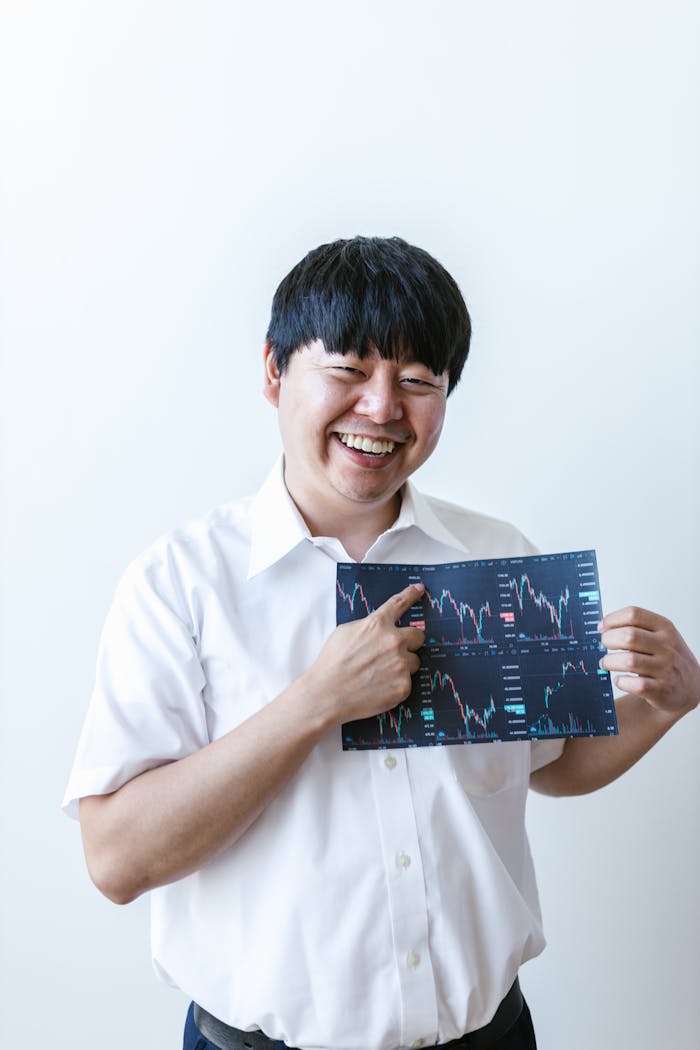 Smiling man holding a stock market chart, representing finance and trading.